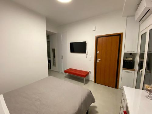 雅典Modern studio apartment B的一间卧室配有一张床、一个红色长凳和一台电视。