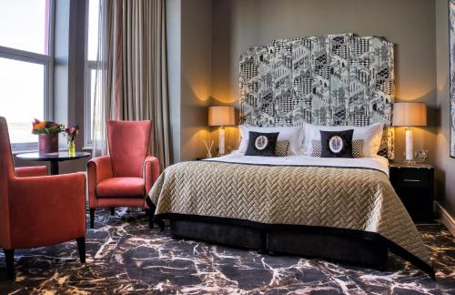波特拉什Elephant Rock Hotel的一间卧室配有一张大床和一张红色椅子