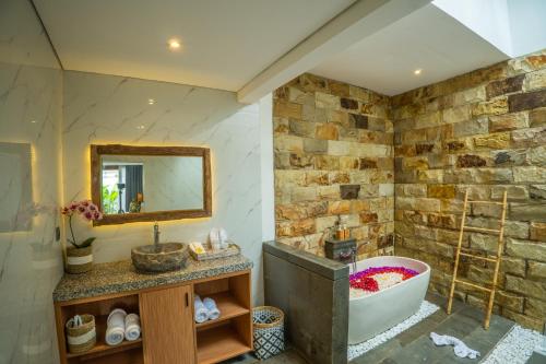 勒吉安Alam Jepun Villa的带浴缸和石墙的浴室