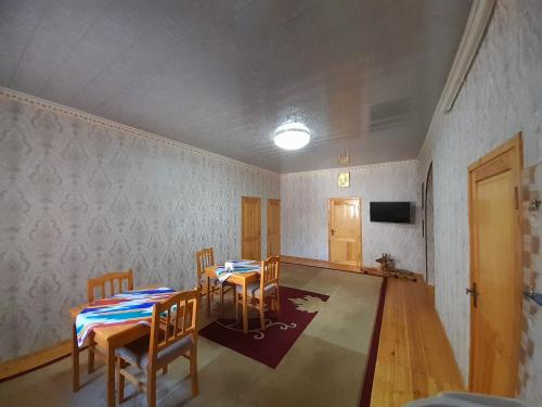 希瓦KHIVA ABDULLA Guest House的一间带2张桌子和椅子以及电视的房间