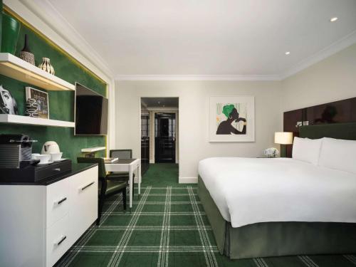伦敦索菲特伦敦圣詹姆士酒店的配有一张床和一张书桌的酒店客房