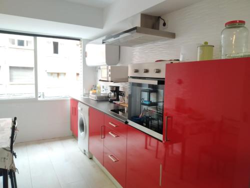希洪Apartamento GIJON LOS CAMPOS的一间厨房,配有红色橱柜和大窗户