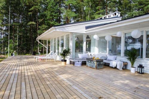 赫尔辛基Villa Dyyni - South Facing - Seafront - Jacuzzi的木制甲板上配有白色家具的凉亭