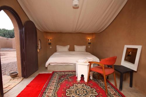 Foum ZguidHOTEL Bab Rimal的卧室配有1张床、1张桌子和1把椅子