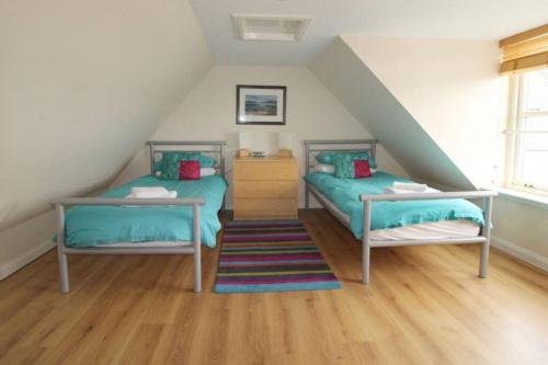 斯托诺韦Castle View Stornoway的阁楼卧室设有两张床和楼梯。