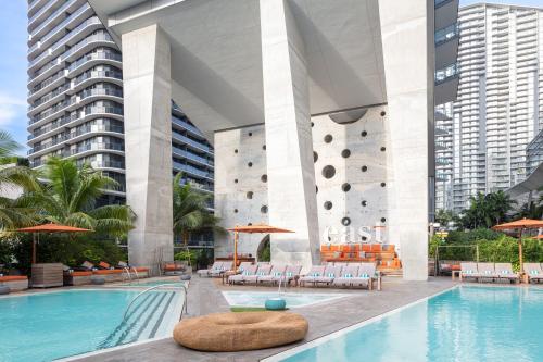 迈阿密EAST Miami Residences的酒店游泳池设有椅子,酒店大楼设有大型游泳池