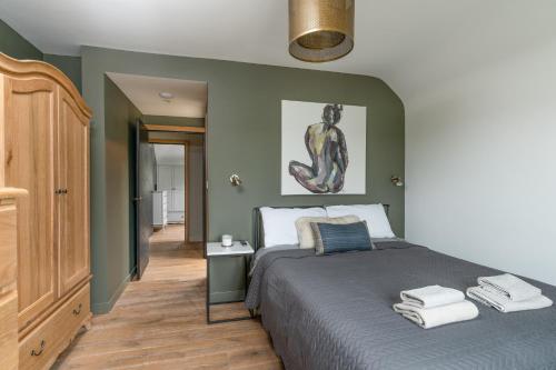泰特伯里Designer Cotswold post house with external sauna的一间卧室设有一张带绿色墙壁的大床