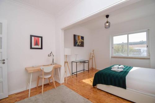 里斯本Cozy and Sunny Family Apartment的一间卧室配有一张床、一张书桌和一个窗户。