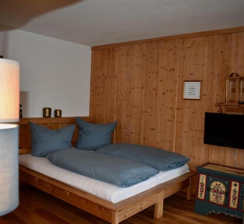 加尔米施-帕滕基兴Apartment Pfanzelter的木墙上的一张带蓝色枕头的床