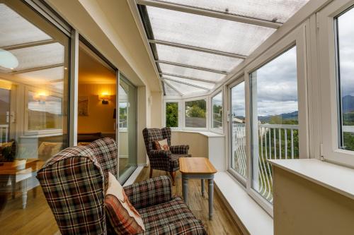 金洛赫兰诺赫Loch Rannoch Highland Club的门廊上设有两把椅子和窗户,