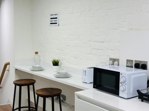 伦敦The Grand M London city的厨房配有带微波炉和2张凳子的台面