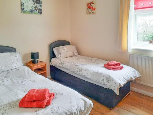 GoxhillCowslip Cottage- W43122的卧室内的两张床,上面有红色毛巾