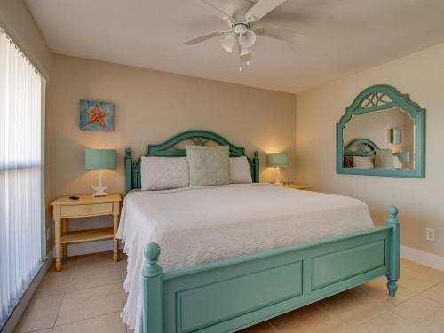 珊瑚角Villa Cosima的一间卧室配有绿色的床和吊扇