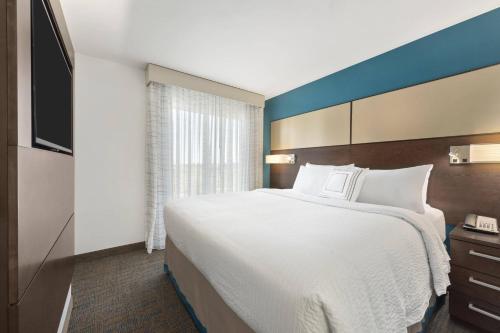 伍德伯里伍德伯里圣保罗万豪原住客栈的酒店客房设有一张大床和一台电视。