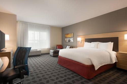 迪比克TownePlace Suites by Marriott Dubuque Downtown的酒店客房带一张大床和一把椅子