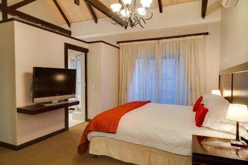 斯泰伦博斯Protea Hotel by Marriott Dorpshuis & Spa Stellenbosch的一间卧室配有一张大床和一台平面电视