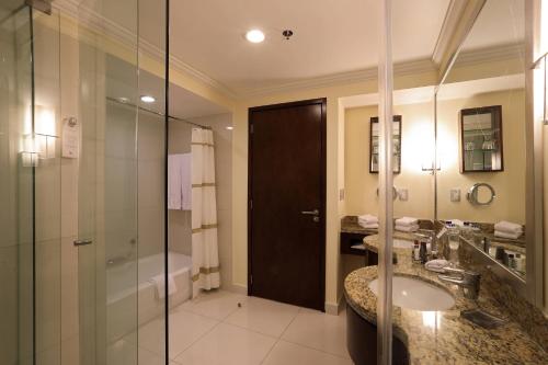 阿瓜斯卡连特斯阿瓜斯卡连特斯万豪酒店的带淋浴和水槽的浴室以及玻璃门。