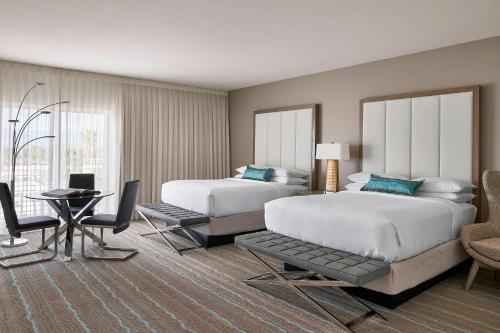 棕榈荒漠帕西奥傲途格精选酒店的酒店客房带两张床和一张桌子以及椅子。