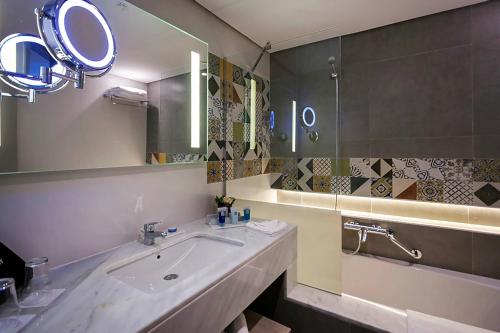 苏塞Sousse Pearl Marriott Resort & Spa的浴室配有盥洗盆、镜子和浴缸