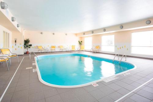 奥什科什奥什科什费尔菲尔德套房酒店的大型客房内的游泳池,配有桌椅