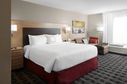 坦帕TownePlace Suites by Marriott Tampa South的酒店客房带一张大床和一把椅子