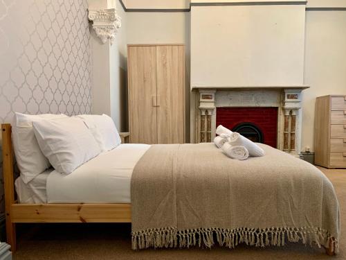 WillenhallSomerford Place - 6 Beds - Sleeps 12 - Parks 2-3 cars/vans的一间卧室配有一张带白色枕头的床和壁炉