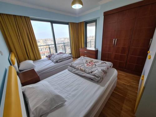 亚历山大LUXURY HOTEL APARTMENT AT GRAND PLAZA SAN STEFANO, PRIME LOCATION, MEGA MALL at ALEXANDRIA的一间卧室设有两张床和大窗户