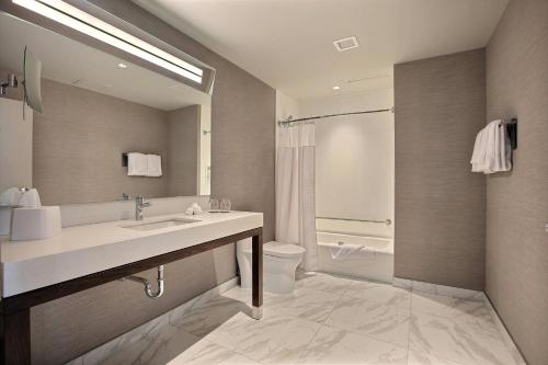 布罗瑟德Courtyard by Marriott Montreal Brossard的一间带水槽、卫生间和镜子的浴室