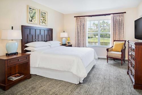 圣露西港Sheraton PGA Vacation Resort Port St Lucie的卧室配有一张白色大床和一把椅子