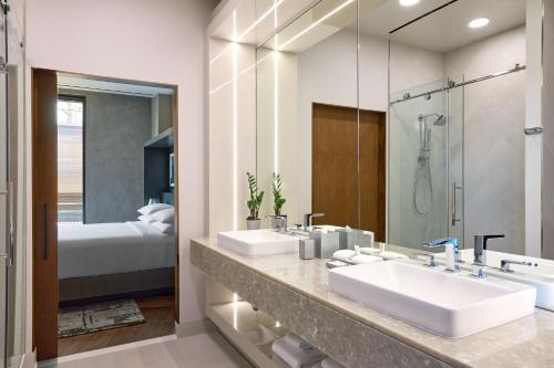 华盛顿Washington Marriott Capitol Hill的一间带两个盥洗盆和镜子的浴室以及一张床