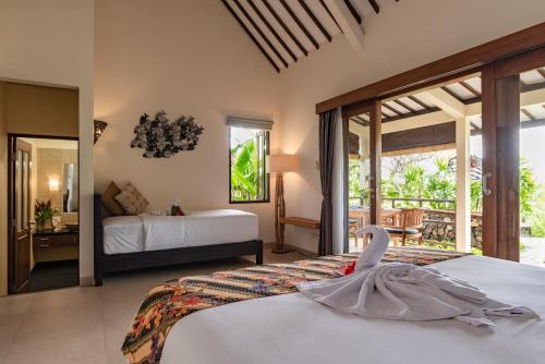 罗威那Alamanda Lovina Resort的一间卧室配有两张床,床上有天鹅