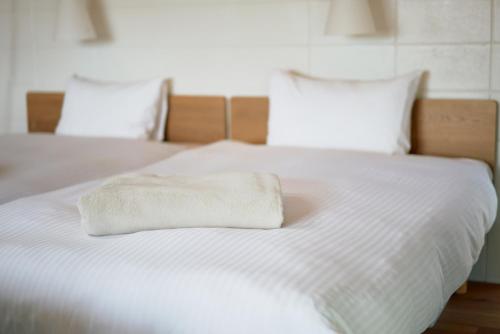 读谷村オーシャンビュー非日常を味わえる空間プライベートバーベキューm yomitan nagahama的一张白色的床,上面有一条折叠毛巾