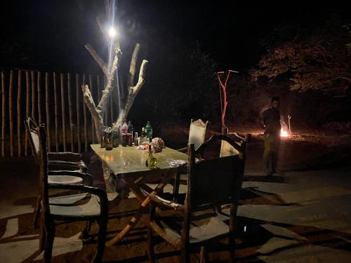 蒂瑟默哈拉默Yala Wild Safaris Camp的一张桌子,椅子,晚上还有一棵树