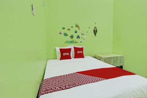 三宝垄OYO 92467 Cahyo Kost 1的一间卧室配有一张带两个红色枕头的床