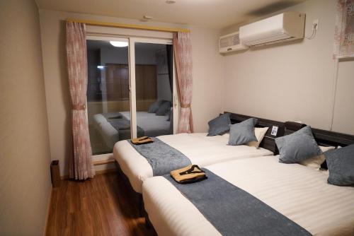 函馆Hakodate MOTOMACHI guesthouse的客房设有两张床和窗户。