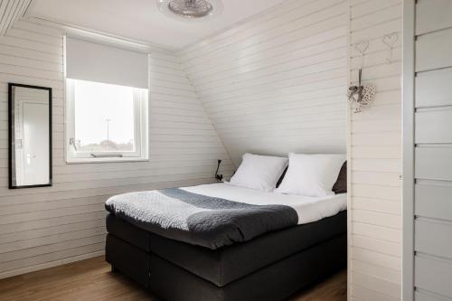 佩滕Strandhuis de Zeeparel met hottub的卧室配有带白色墙壁和窗户的床