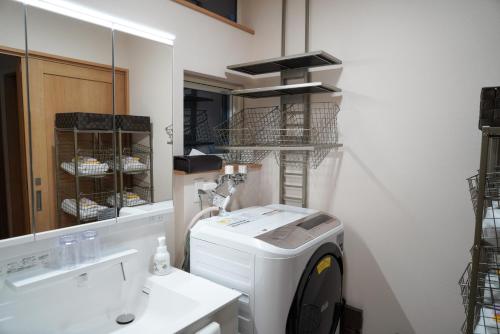 函馆Hakodate MOTOMACHI guesthouse的洗衣房配有洗衣机和镜子