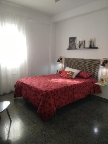 塞维利亚Sevilla Macarena apartamento 3 dormitorios的一间卧室配有一张带红色毯子的床和窗户。