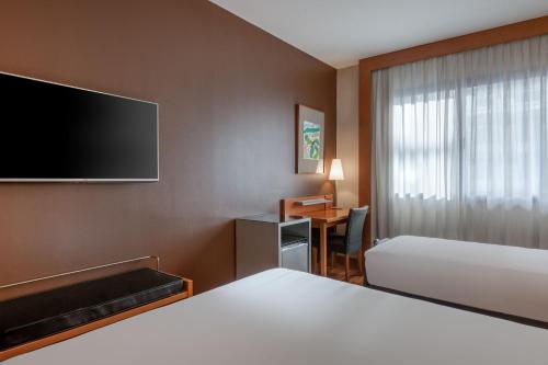莱昂AC Hotel León San Antonio by Marriott的酒店客房设有一张床、一张书桌和一台电视机。