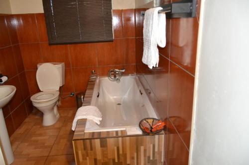 LesomaChobe Sunset Chalets的带浴缸和卫生间的浴室。