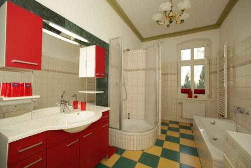 普特布斯Villa Schulenburg in Putbus auf Rügen的一间带红色橱柜、浴缸和水槽的浴室