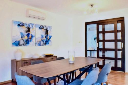 拉纳卡Ilios Villa的一间带木桌和蓝色椅子的用餐室