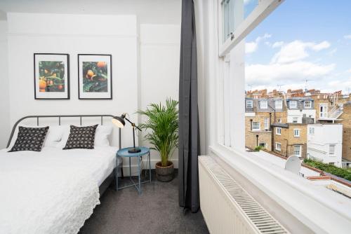 伦敦Kensington Nest Serviced Town House的一间卧室设有一张床和一个大窗户
