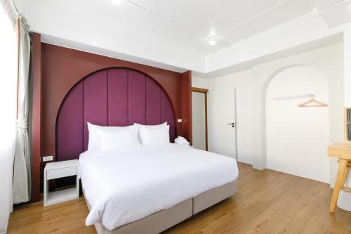 清莱Grow home -Stay and space, Self check-in的一间卧室配有一张白色大床和紫色床头板