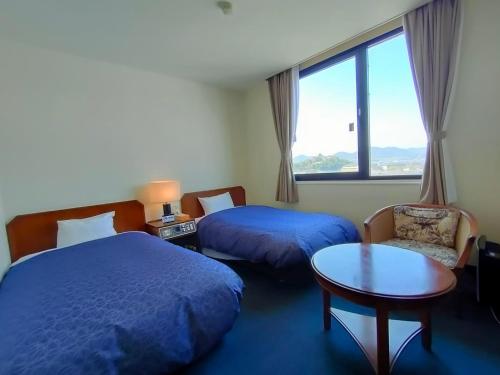 犬山市Inuyama City Hotel的酒店客房设有两张床、一张桌子和一个窗户。