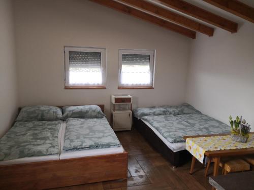 Poľný KesovCeremoniár的配有2张床的带桌子和2扇窗户的客房