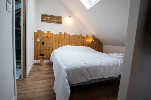 厄镇Escapade Eudoise的卧室配有一张白色大床和木制床头板