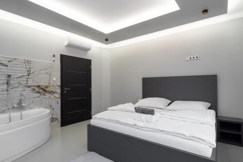 俄斯特拉发OŽA apartmány的一间白色卧室,配有一张床和一个浴缸