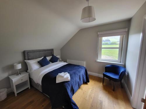 DunquinDunquin House Bed and Breakfast的一间卧室配有一张带蓝色椅子的床和窗户