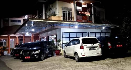BangkinangHotel Al Madinah Bangkinang的两辆汽车停在大楼前的停车场
